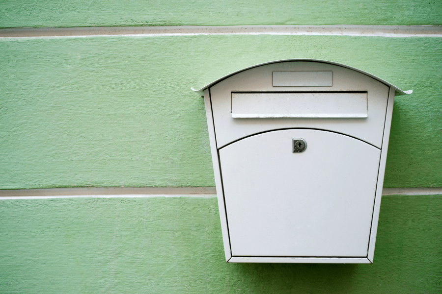 Ein weißer Briefkasten an einer grünen Wand